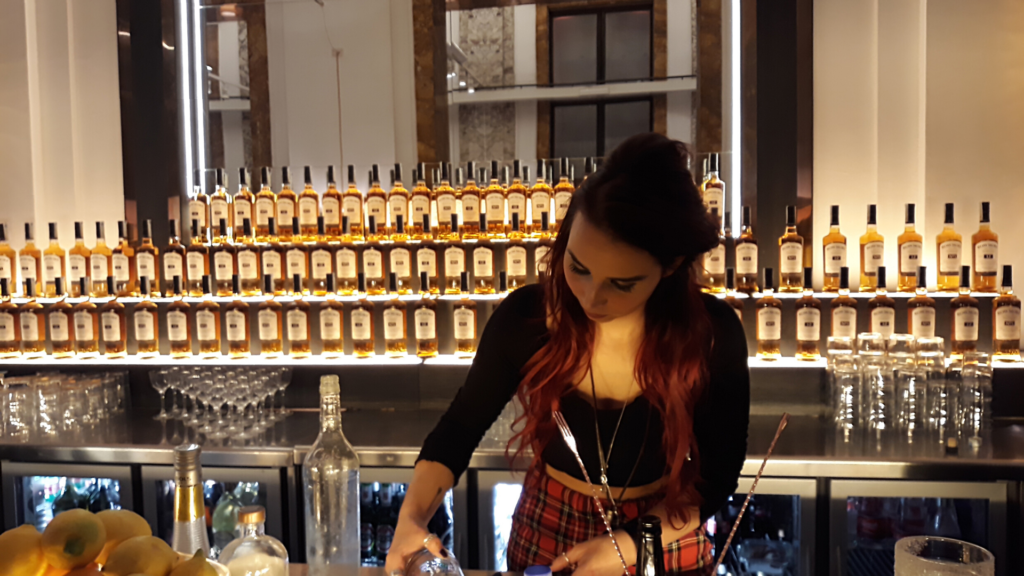 Barlady e sullo sfondo bottiglie di whisky